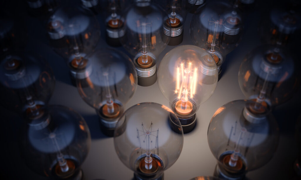 Light bulb glowing among multiple dim bulbs, symbolizing innovation and clarity in IT asset disposal and management.
