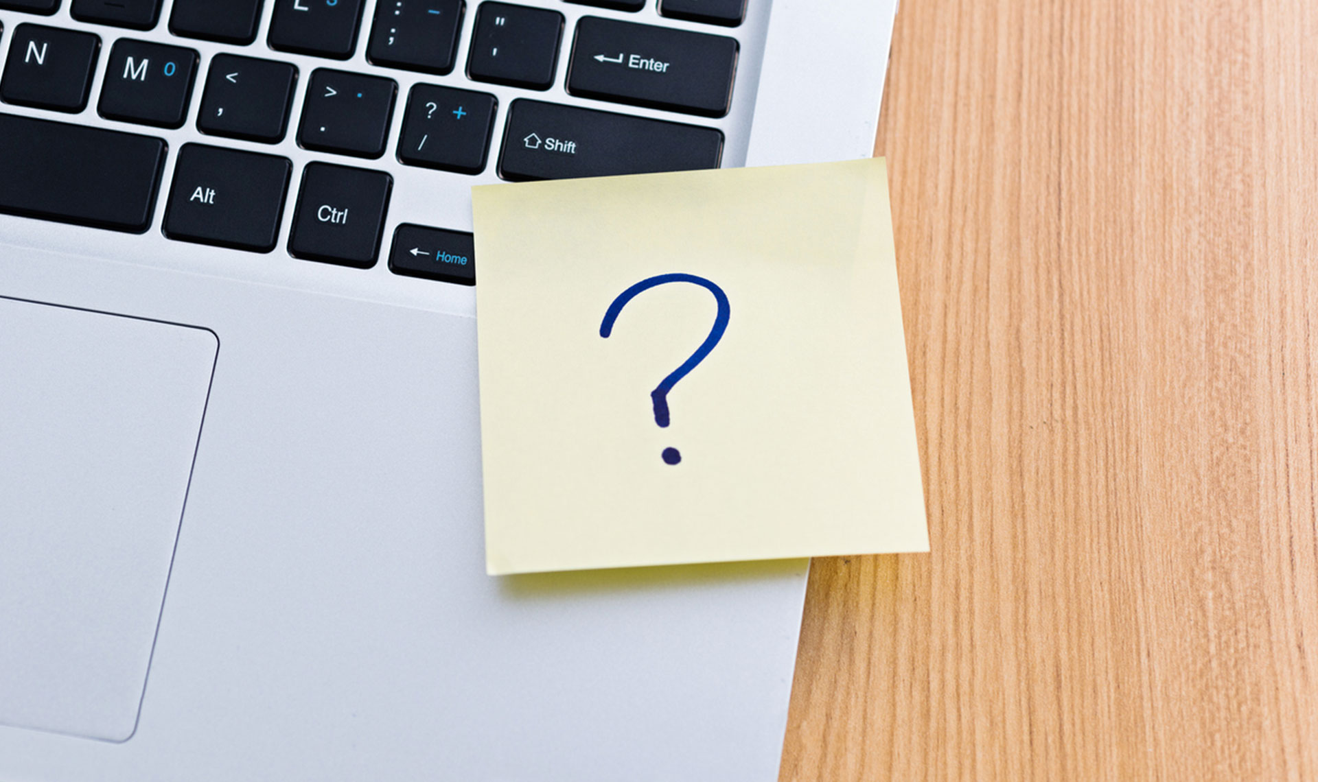 Post-it note with question mark on, placed on laptop