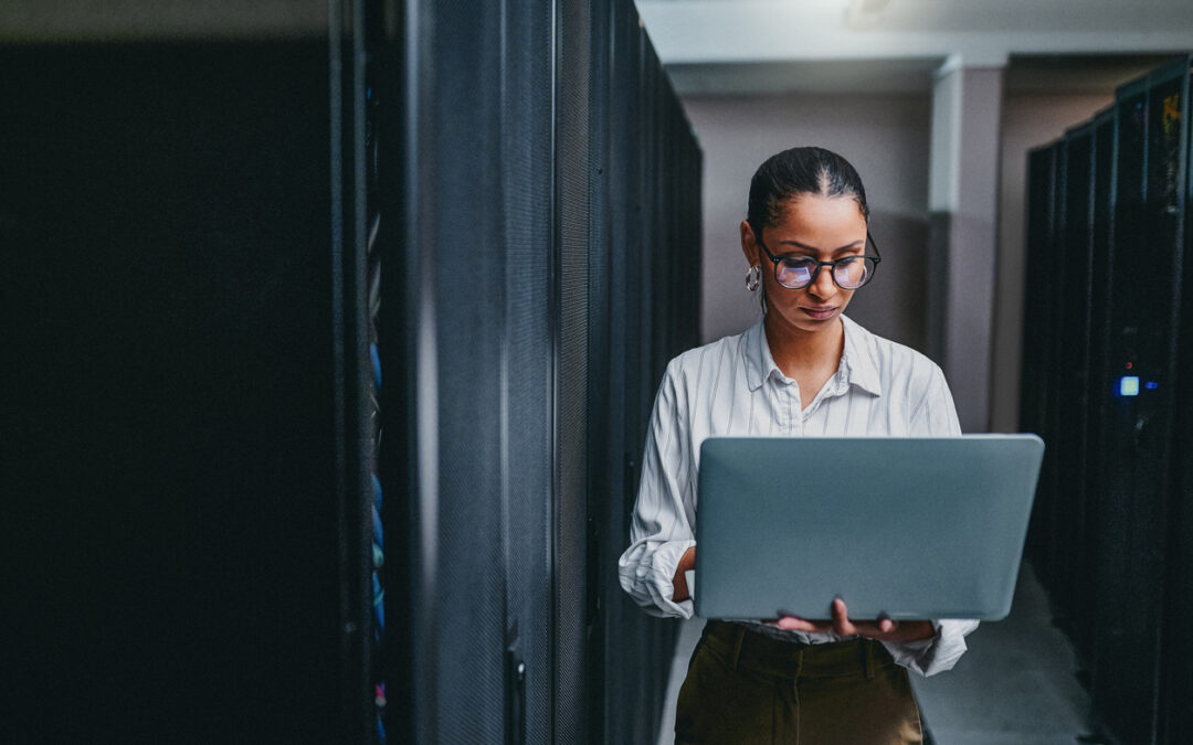 Woman in a data centre using a laptop, representing IT asset disposal and data security services by Astralis Technology Ltd.