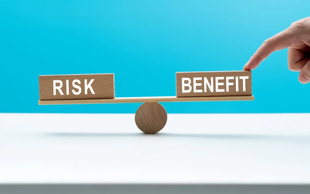 Wooden balance scale with blocks labeled "RISK" and "BENEFIT," representing the evaluation of risks and benefits in IT asset disposal and management.