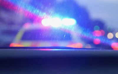 Police vehicle with flashing blue and red lights seen through a car windshield, illustrating road safety and law enforcement context.