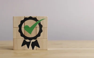 Wooden blocks arranged to form a certification badge with a green checkmark, symbolizing quality assurance and compliance in IT asset management.