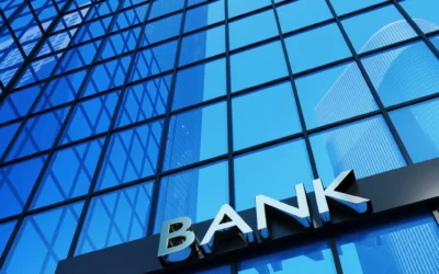 Modern bank building facade with large glass windows reflecting blue sky, featuring prominent 'BANK' signage, relevant to IT asset disposal and compliance in financial services.